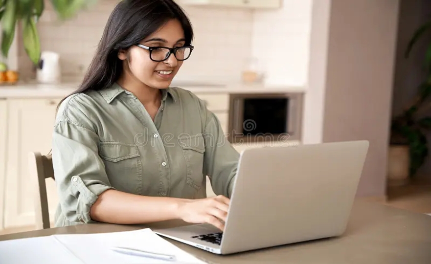 Woman with glasses working happily on laptop, representing successful appointment rescheduling